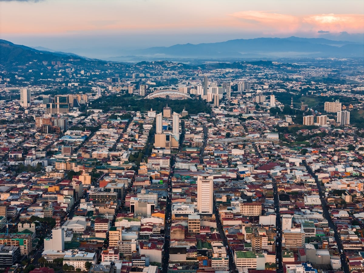 Vista aérea de ciudad con montañas al fondo representando Costa Rica digital