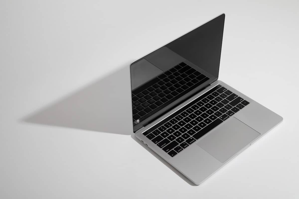 MacBook Pro sobre mesa blanca con teclado y trackpad visibles